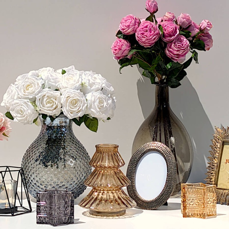 Cadre photo ovale bronze associé à un vase en verre et un bouquet de roses sur une console.