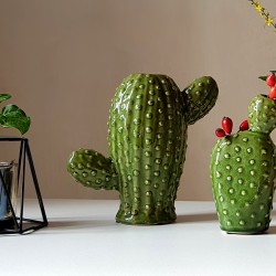 Duo de vases cactus en céramique verte brillante posés sur une table blanche.