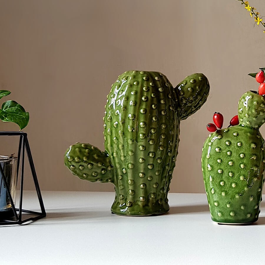 Duo de vases cactus en céramique verte brillante posés sur une table blanche.