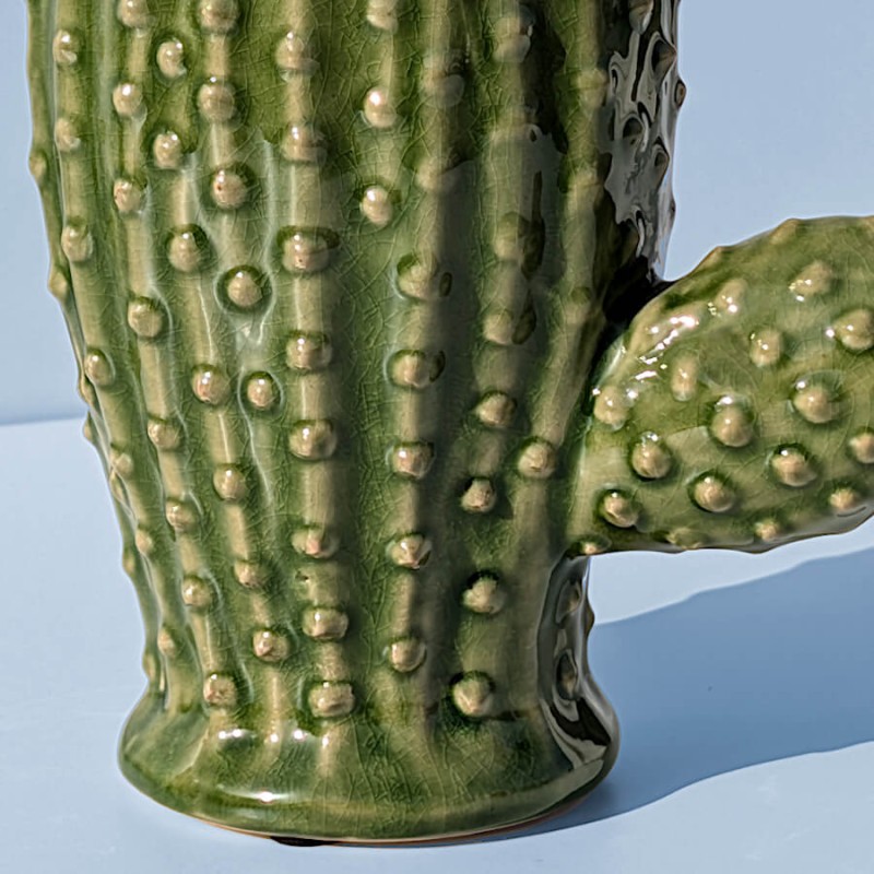 Gros plan sur la texture émaillée et les picots en relief du vase cactus vert.