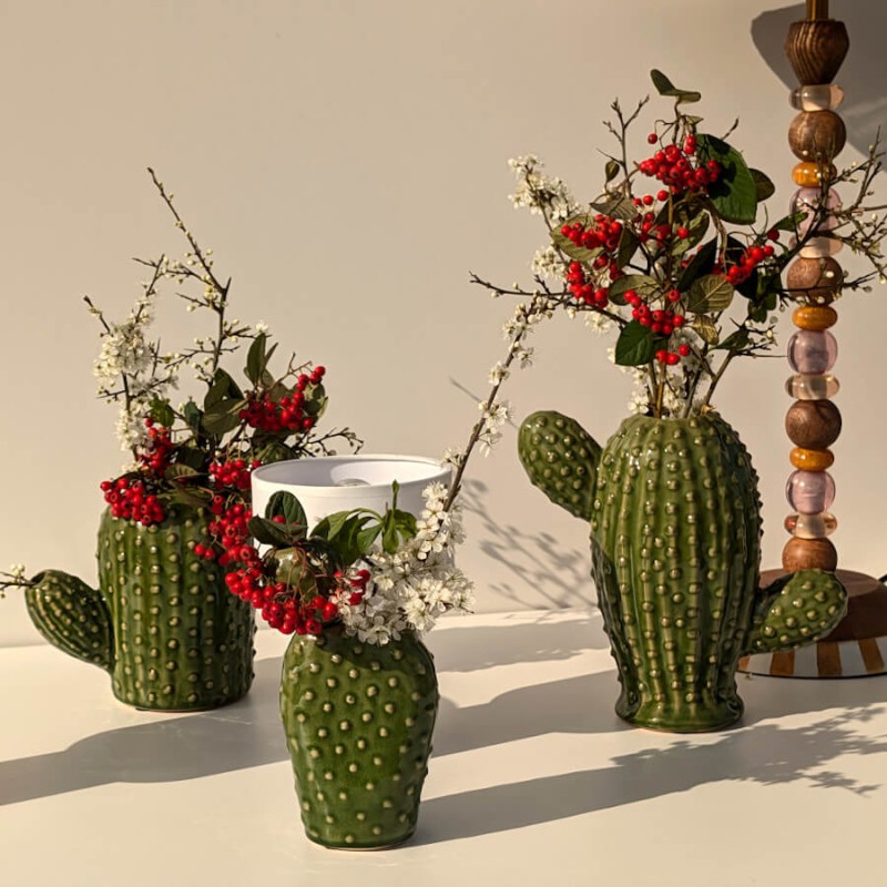 Trio de vases cactus en céramique verte accueillant des branches de prunier en fleurs.