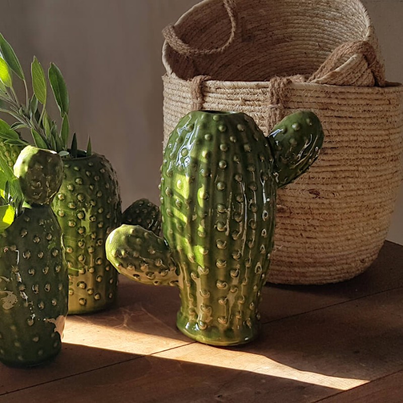 Vases cactus en céramique verte associés à un panier tressé en fibre naturelle sous lumière rasante.