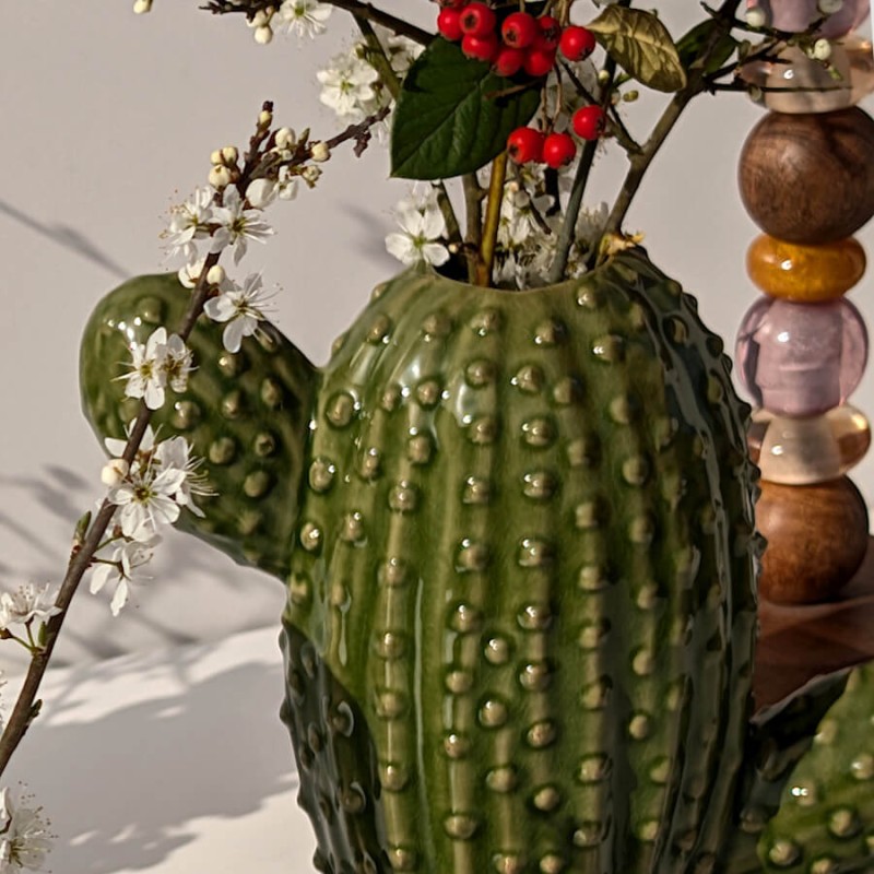 Zoom sur les branches de fleurs blanches émergeant du vase cactus en céramique émaillée.