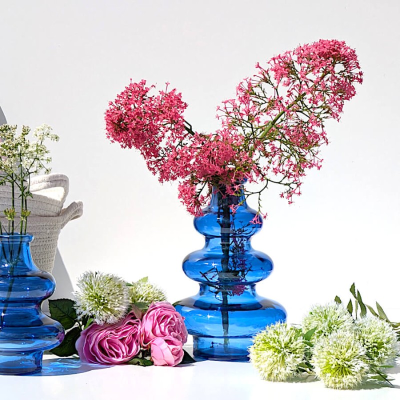 Vase 3 boules en verre bleu cobalt accueilliant un généreux bouquet de fleurs roses.