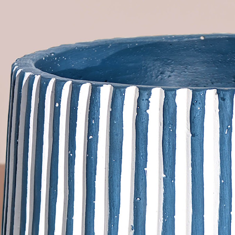Gros plan sur les cannelures texturées et la peinture à rayures bleu capri du bord du cache-pot.