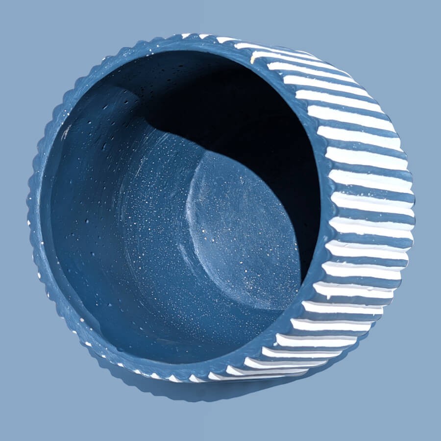 Vue en plongée de l'intérieur bleu profond du cache-pot en céramique à rayures blanches et bleues.