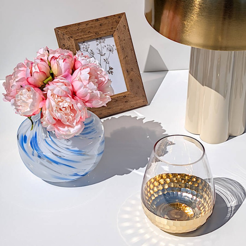 Ensemble déco lumineux avec le vase opalin bleu garni de pivoines, le cadre bois et le photophore doré.