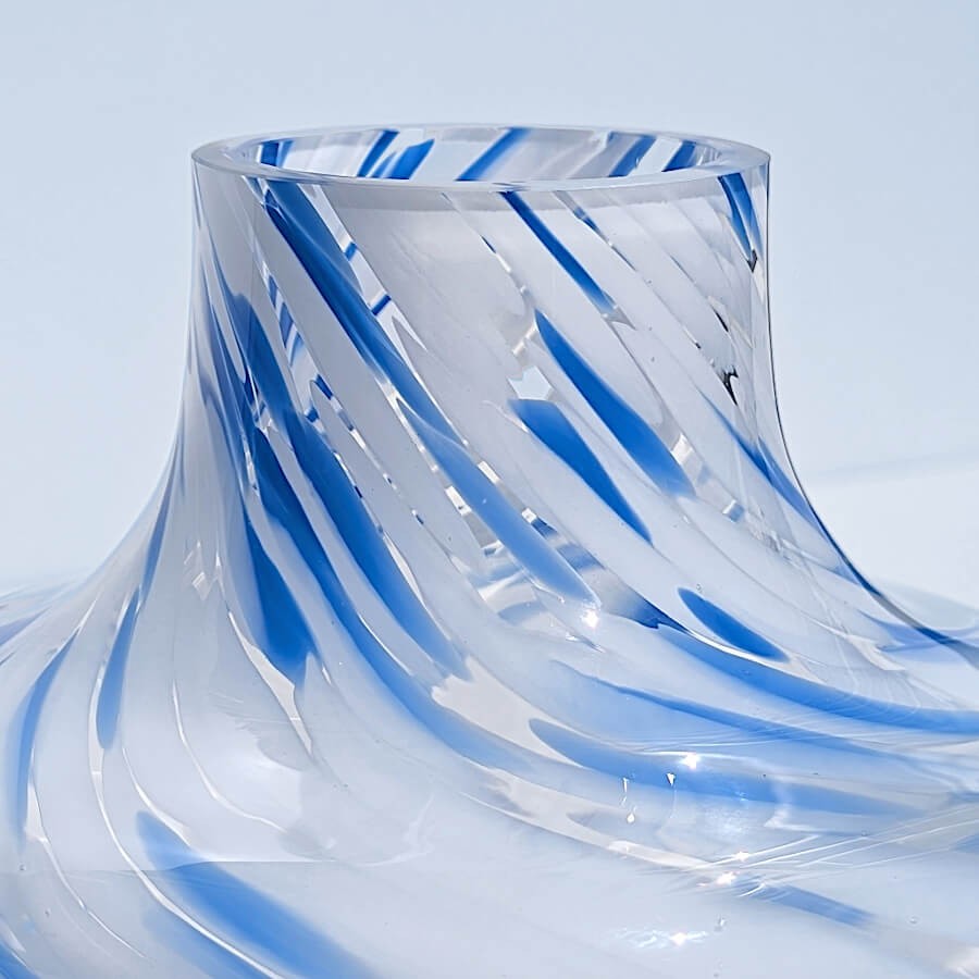Gros plan sur la finition du col et les volutes de verre bleu du vase opalin.