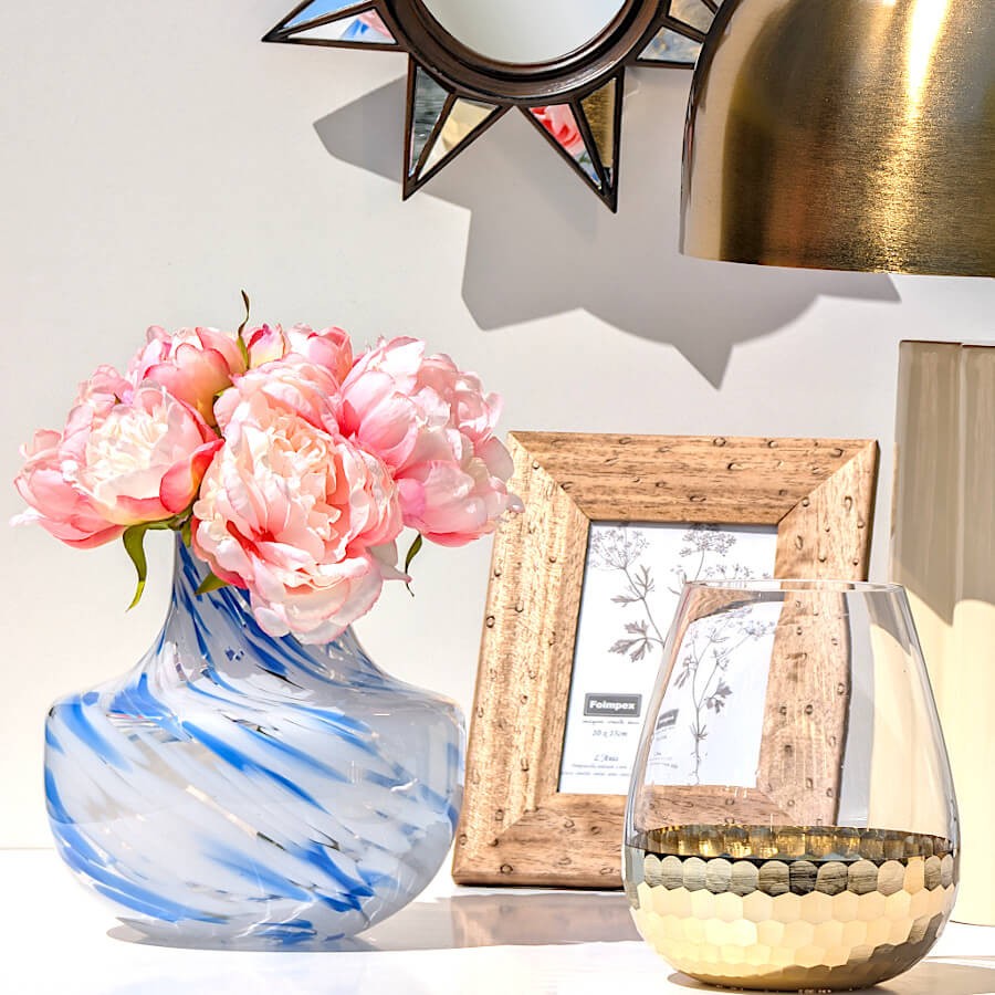 Composition élégante avec pivoines roses dans le vase opalin bleu et miroir soleil doré en arrière-plan.