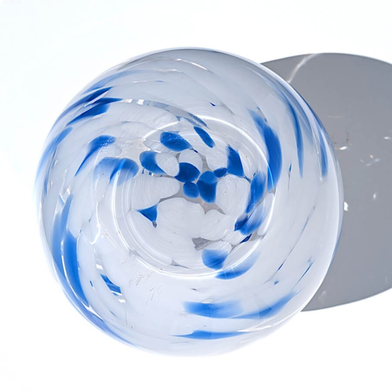 Vue plongeante directe sur le fond et les motifs tourbillonnants bleus du vase en verre soufflé.