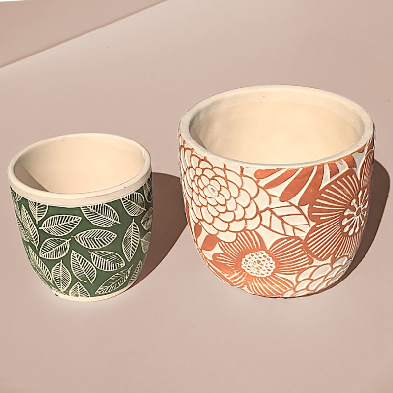 Duo de cache-pots en ciment, l'un vert à feuilles et l'autre terracotta à fleurs seventies.