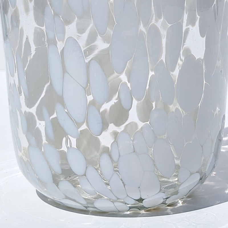 Gros plan sur la texture du verre transparent et les confettis blancs incrustés dans la matière.