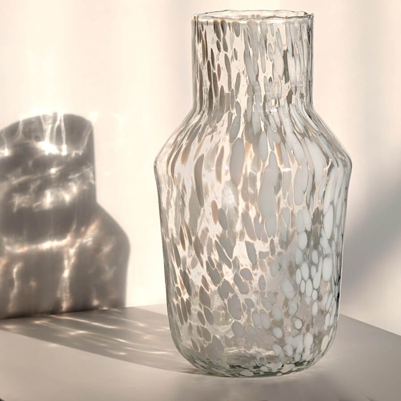 Effet d'ombre portée poétique du vase en verre moucheté blanc sous la lumière naturelle.