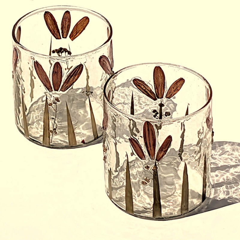 Vue rapprochée de deux photophores en verre aux motifs floraux et végétaux naturels.